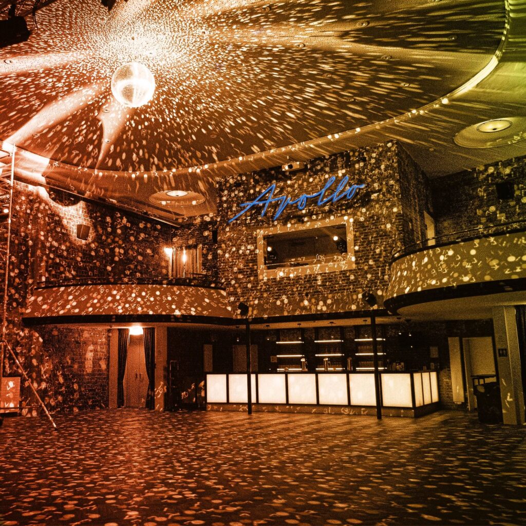 Tanzfläche im Apollo Club mit leuchtender Diskokugel, beleuchteter Bar und Retro-Atmosphäre.