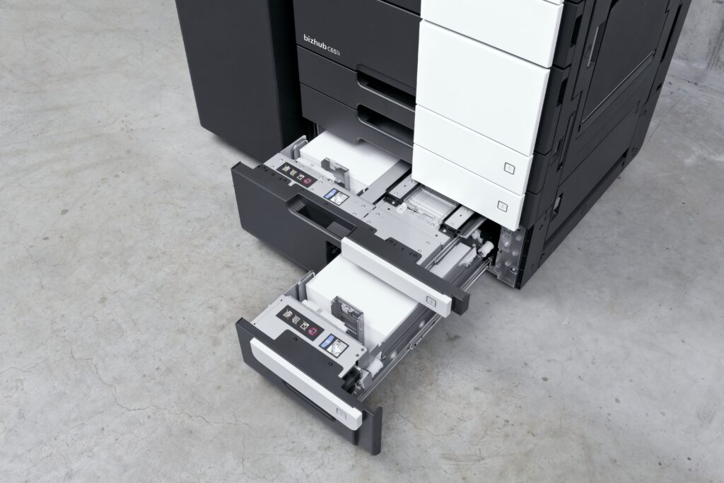 Offene Papierfächer eines modernen Multifunktionsdruckers zeigen die verschiedenen Papierzuführungen und Einstellungen.