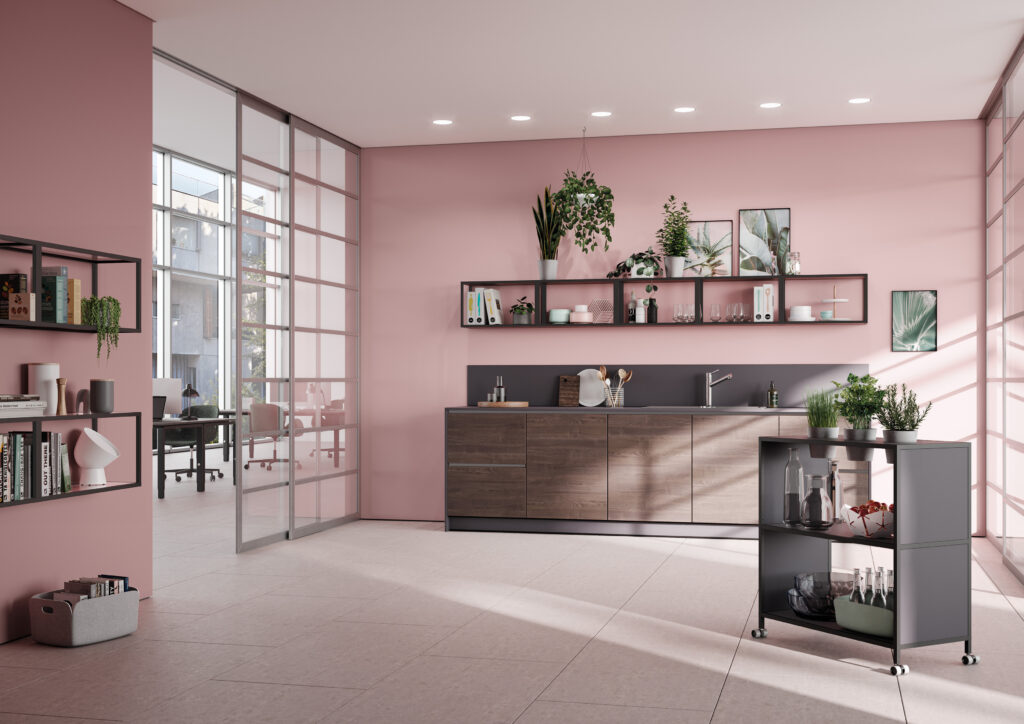Moderne Büroküche mit rosa Wänden, Holzfronten und offenen Regalen mit Pflanzen und Geschirr.