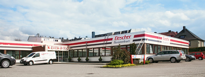 Außenansicht des Döscher Bürocentrums mit Firmenbeschriftung, geparkten Autos und Lieferwagen auf dem Parkplatz.