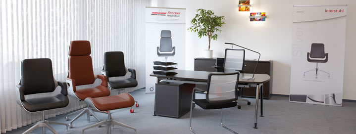 Modern eingerichtetes Büro mit Schreibtisch, ergonomischen Bürostühlen und Werbebannern der Marke Interstuhl.